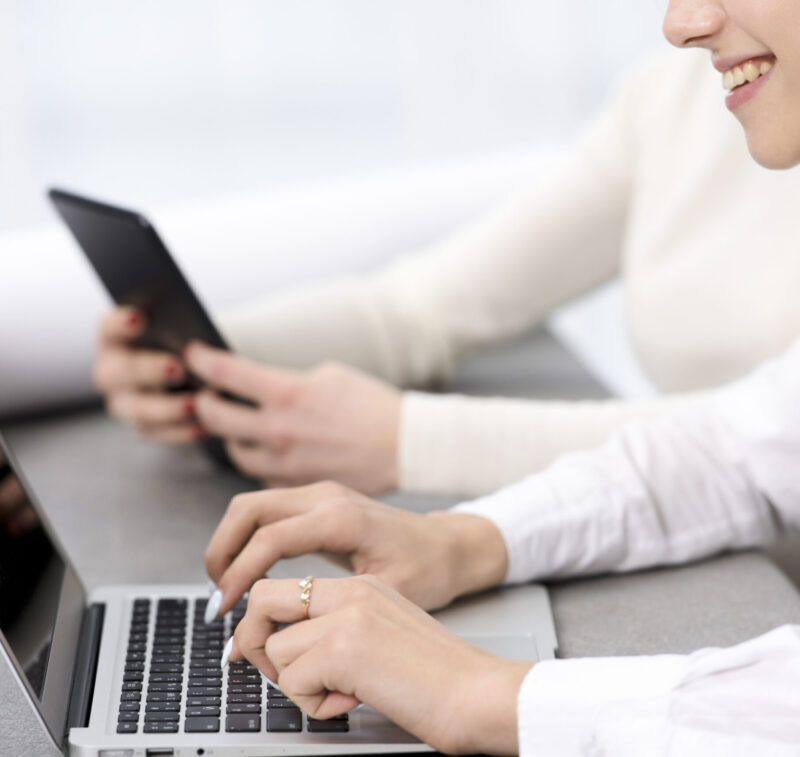 smiling-young-businesswoman-typing-laptop-desk